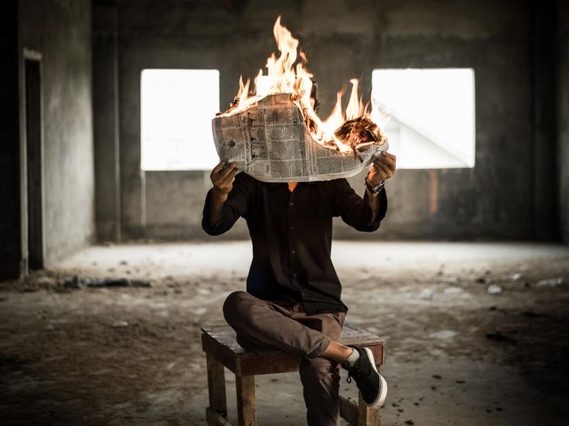 مرد در حال مطالعه‌ی روزنامه‌ای که آتش گرفته است