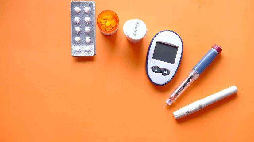 دستگاه تست قند خون و انسولین و وسایل مربوط به بیماری دیابت روی یک صفحه‌ی نارنجی